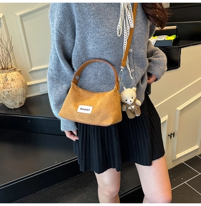 Detail of tan suede handbag with MJJ137 patch, top handle and cute bear charm