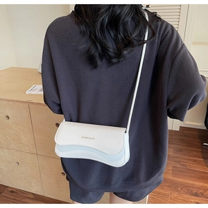 Close-up of a cream-white crossbody bag with gold Fashion & Bags lettering on a model