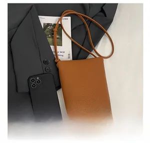 Close-up of brown lychee grain leather phone bag with slim shoulder strap and logo
