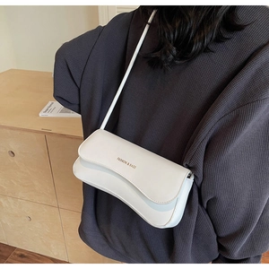 Detail of a minimalist white leather underarm bag with gold logo text on the flap