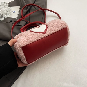 Détail du sac cylindrique en polaire rose avec cuir rouge et motif cœur blanc
