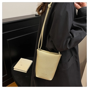 Detail of champagne gold bucket bag with litchi grain texture and brand embossing