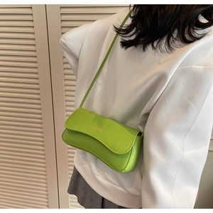 Detail view of neon green baguette bag featuring golden Fashion & Bags text on faux leather