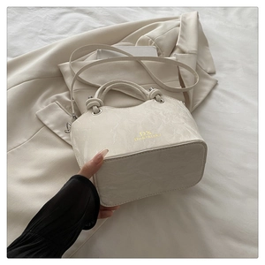 Detail of cream white handbag featuring elegant marble texture and gold DX logo