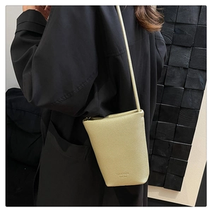 Detail of a beige litchi grain mini bucket bag with embossed Forever Young logo