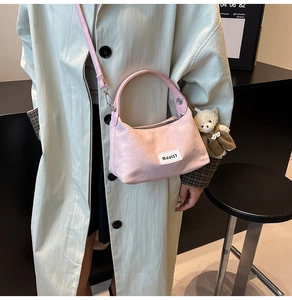 Detail of pink canvas crossbody bag with white mddj37 woven label and cute bear charm