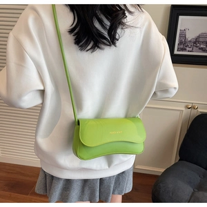 Detail view of fruit green leather crossbody bag with gold Fashion & Bags logo on model