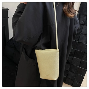 Detail of a beige pebbled leather phone bag featuring an embossed logo on the bottom