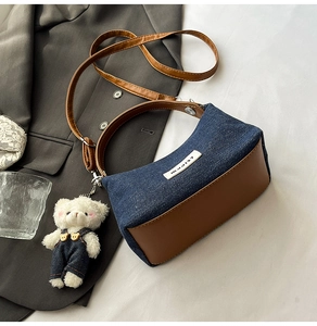 Detail of denim and leather shoulder bag with adjustable strap and cute teddy bear charm