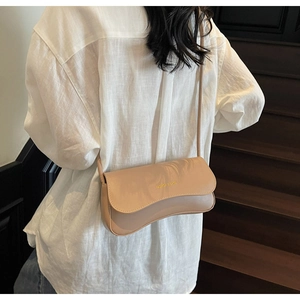 Minimalist beige crossbody bag on a model showing smooth leather finish and gold logo detail