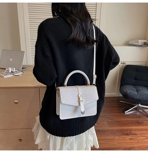 Détail montrant la texture tissée blanche et le fermoir métallique du sac à bandoulière