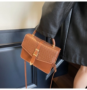 Détail du sac à main en cuir marron avec texture tissée en damier et boucle dorée
