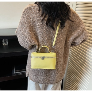 Gros plan d'un sac bandoulière jaune vif en similicuir vu de dos porté par un mannequin