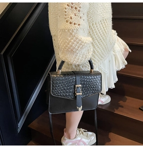 Détail du sac à main en cuir tressé noir avec boucle dorée vintage et bandoulière