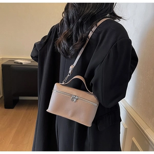 Litchi pattern leather box bag in tan finish shown on a shoulder with black coat