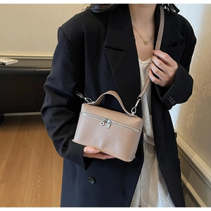 Detail of khaki box-shaped shoulder bag with litchi grain texture and top handle