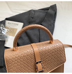 Détail de la texture tissée, de l'anse tressée et de la boucle dorée du sac à main brun