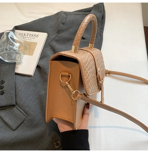 Détail de la texture en cuir tressé beige et ferrures dorées sur ce sac bandoulière