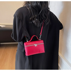 Rear view of a compact red leather crossbody bag worn over a stylish black wool coat