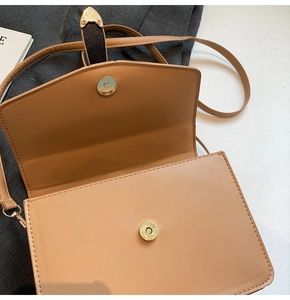 Détail de la boucle magnétique et des garnitures dorées sur le sac à bandoulière beige
