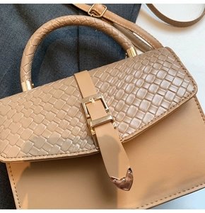 Détail du sac à main marron clair avec rabat tissé et pointes métalliques en forme de cœur