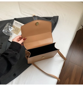 Gros plan sur un sac à main camel avec fermeture magnétique et structure latérale en accordéon