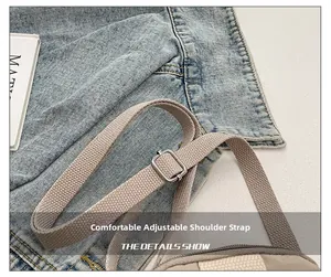 Detailed close-up of adjustable light gray canvas strap with silver metal buckle on bag
