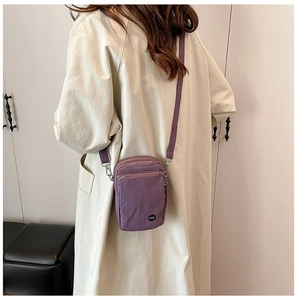 Model wearing a purple multi-layer nylon crossbody bag with adjustable strap and zip detail