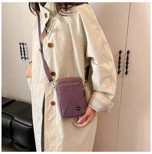Purple nylon crossbody phone bag with brand logo shown on a model in a beige trench coat