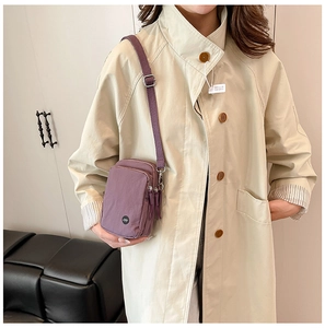 Detail of purple nylon mini crossbody bag showing front zipper pocket and silver metal hooks