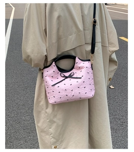 Close-up of pink quilted bag with black ribbon patterns and metallic gold hardware