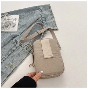 Detail of khaki nylon crossbody bag with adjustable strap and decorative stripes