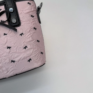 Détail du tissu jacquard rose avec motifs de nœuds noirs et accents en cuir