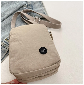 Detail view of khaki nylon crossbody bag featuring double zipper compartments and LYT patch