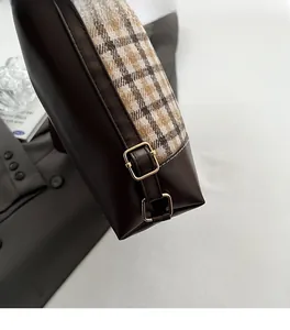 Detail of premium golden metal buckles on plaid canvas and leather tote bag