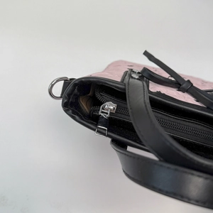 Détail du sac à main rose gaufré avec fermeture éclair noire et métal argenté