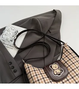 Detail of British check tote bag with brown leather flap and cute teddy bear patch