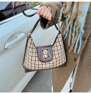Detail of checkered tote bag with teddy bear patch and premium brown leather trim