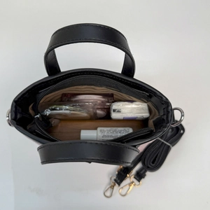 Vue de dessus de l'intérieur d'un mini sac en cuir noir avec doublure et bandoulière amovible
