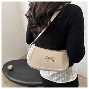 Detail of cream white underarm bag with a golden bow metal buckle on a shoulder strap