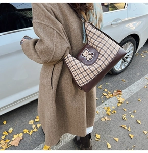 Close-up of a brown plaid tote bag with a cute bear patch embroidery on the side