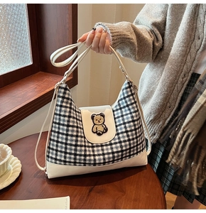 Detail of plaid tote bag featuring a teddy bear patch and premium leather trim details