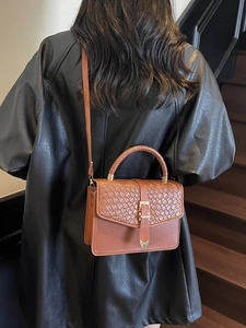 Sac à main vintage marron avec motif tressé et boucle métal porté par mannequin