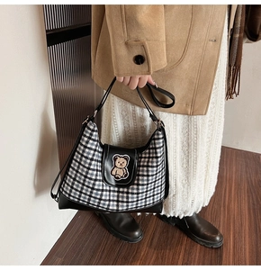 Detail of checkered shoulder bag with leather patchwork and cute bear patch accessory