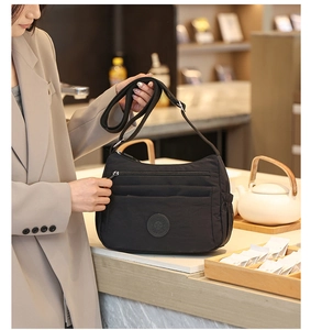 Close-up of black multifunctional crossbody bag with multi-layer zippers and side pockets