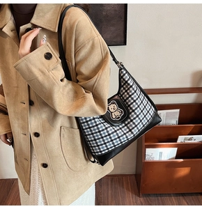 Detail of vintage plaid tote bag with brown bear embroidery patch on a female model