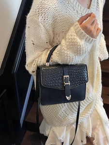 Sac à main élégant en cuir tressé noir avec boucle argentée porté sur une robe en dentelle