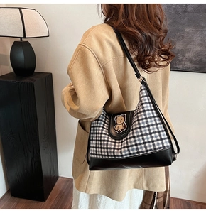 Detail of large check tote bag with brown bear patch and black leather strap trim
