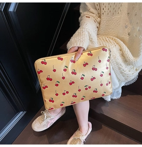 Detail of laptop sleeve with golden metallic finish and red cherry patterns