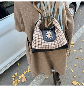 Outdoor shot of a checkered tote bag with bear embroidery and black leather trim